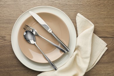 Clean plates and cutlery on wooden table, top view