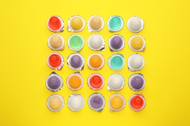 Photo of Tasty bright jelly cups on yellow background, flat lay