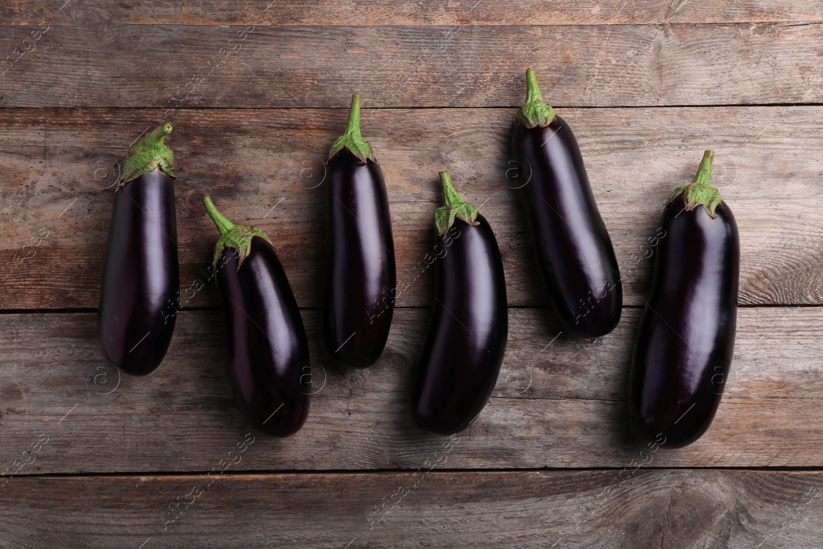 Photo of Raw ripe eggplants on wooden background, top view