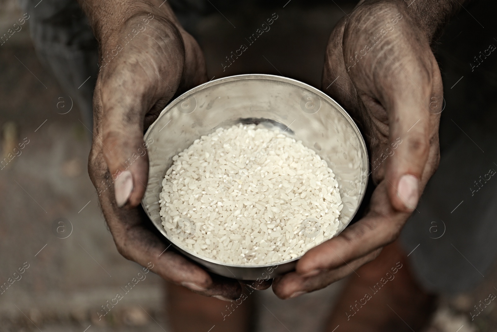 Photo of Poor homeless man with bowl of rice outdoors, closeup