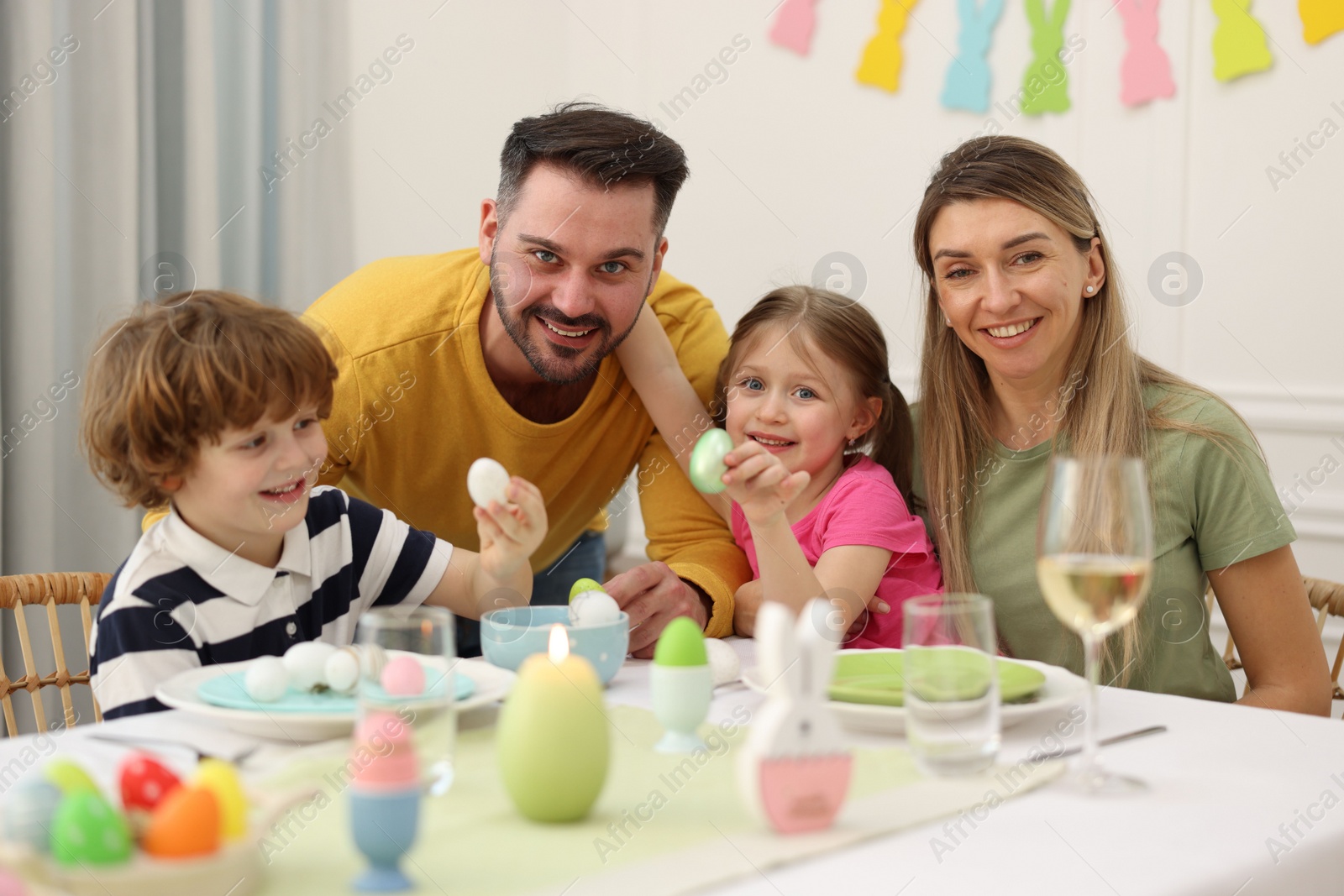 Photo of Happy family celebrating Easter at served table in room