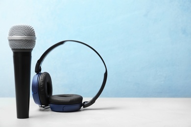 Photo of Headphones and microphone on table against color background. Space for text