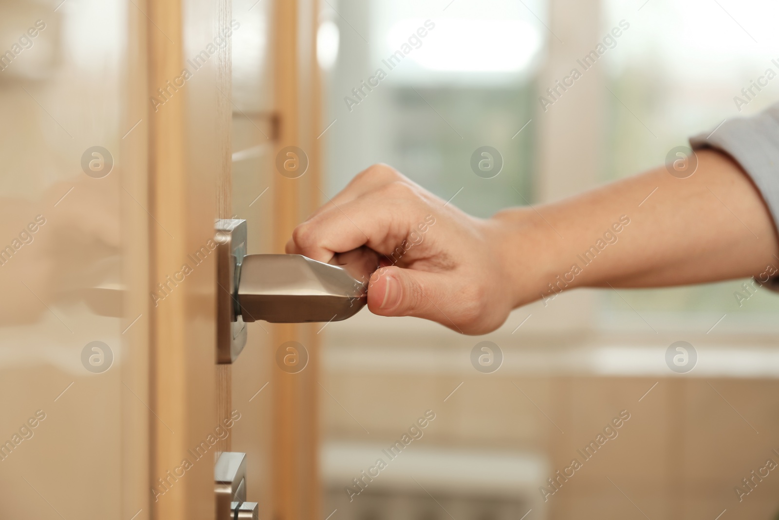 Photo of Woman opening door indoors, closeup of hand