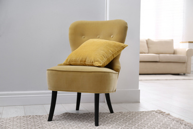 Photo of Comfortable armchair with cushion indoors. Interior element