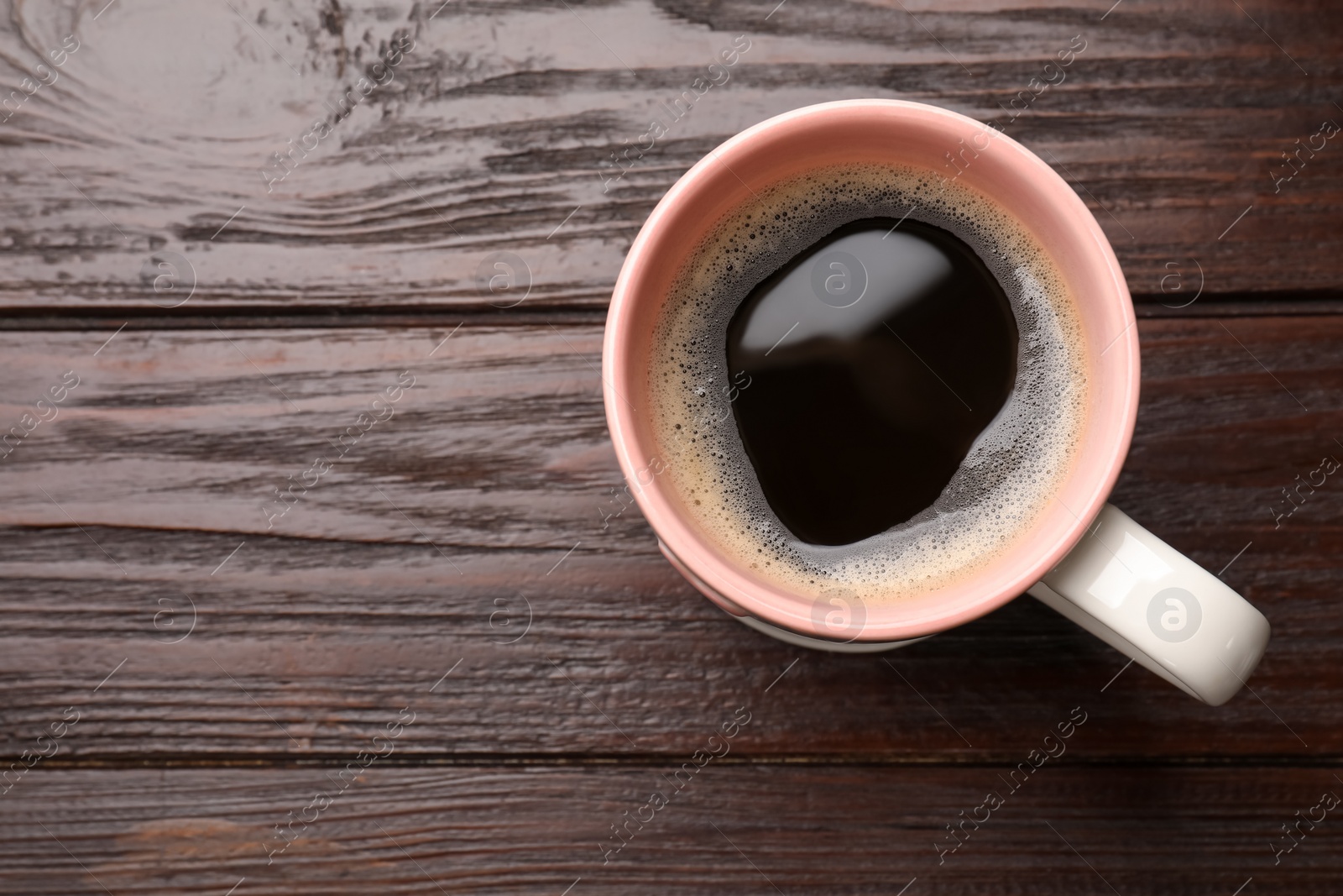 Photo of Cup of aromatic coffee on wooden table, top view. Space for text