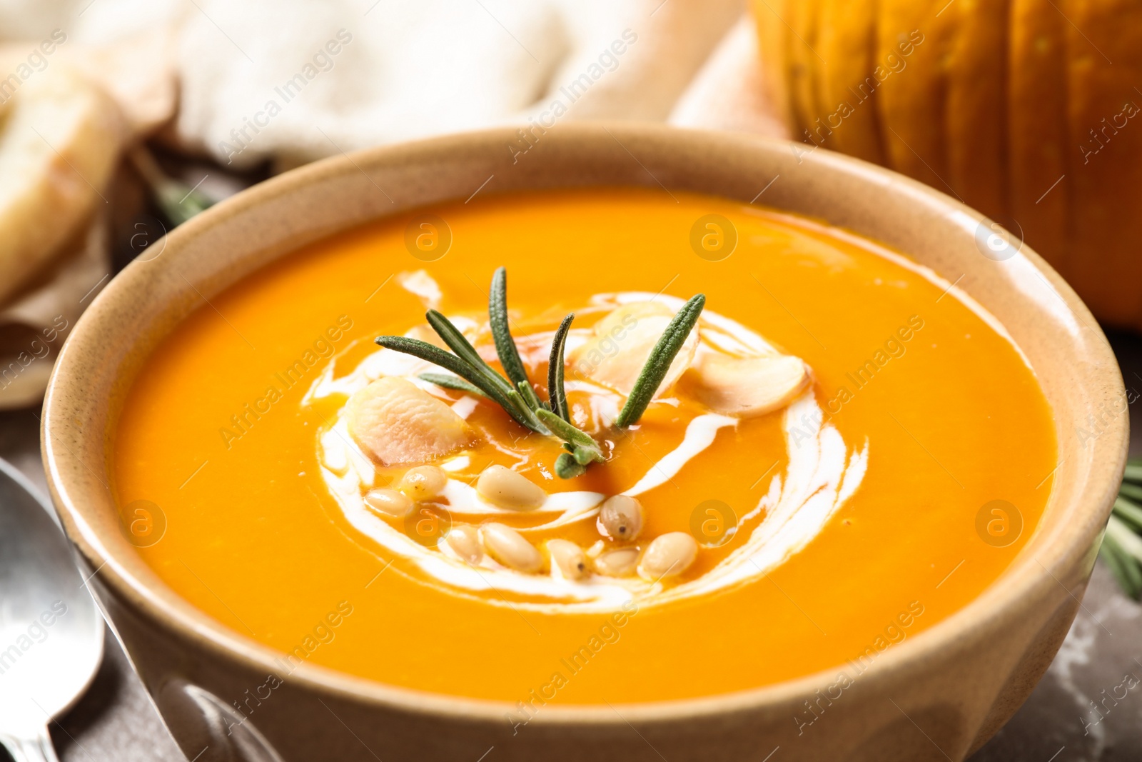 Photo of Delicious pumpkin soup in bowl on table, closeup