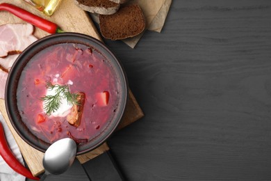 Photo of Tasty borscht with sour cream in bowl served on grey wooden table, flat lay. Space for text