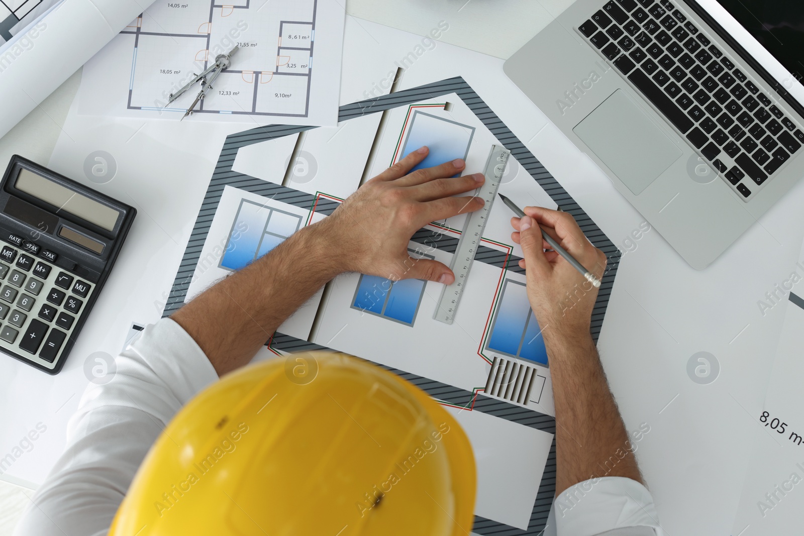 Photo of Architect working with construction drawings at white table, top view