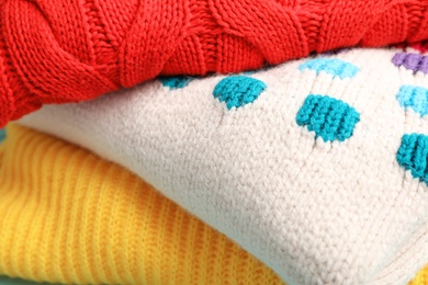 Photo of Stack of folded warm knitted sweaters, closeup