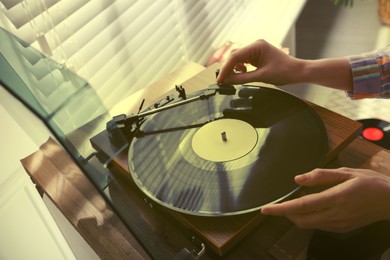 Young woman using turntable at home, closeup