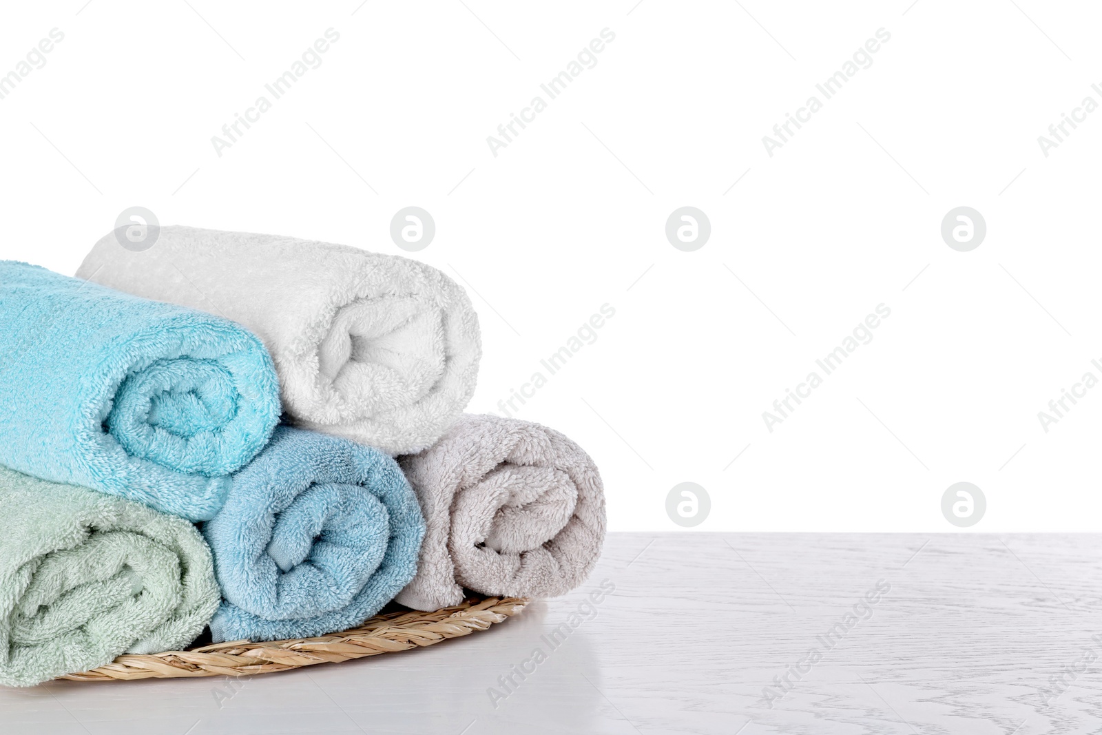 Photo of Fresh towels on wooden table against white background. Space for text