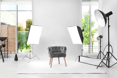 Interior of modern photo studio with armchair and professional equipment