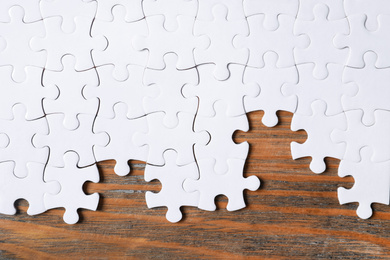 Photo of Blank white puzzle pieces on wooden background, flat lay