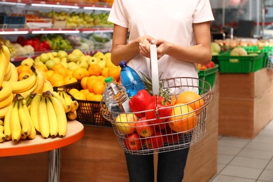 Photo of Woman with shopping basket in supermarket, closeup