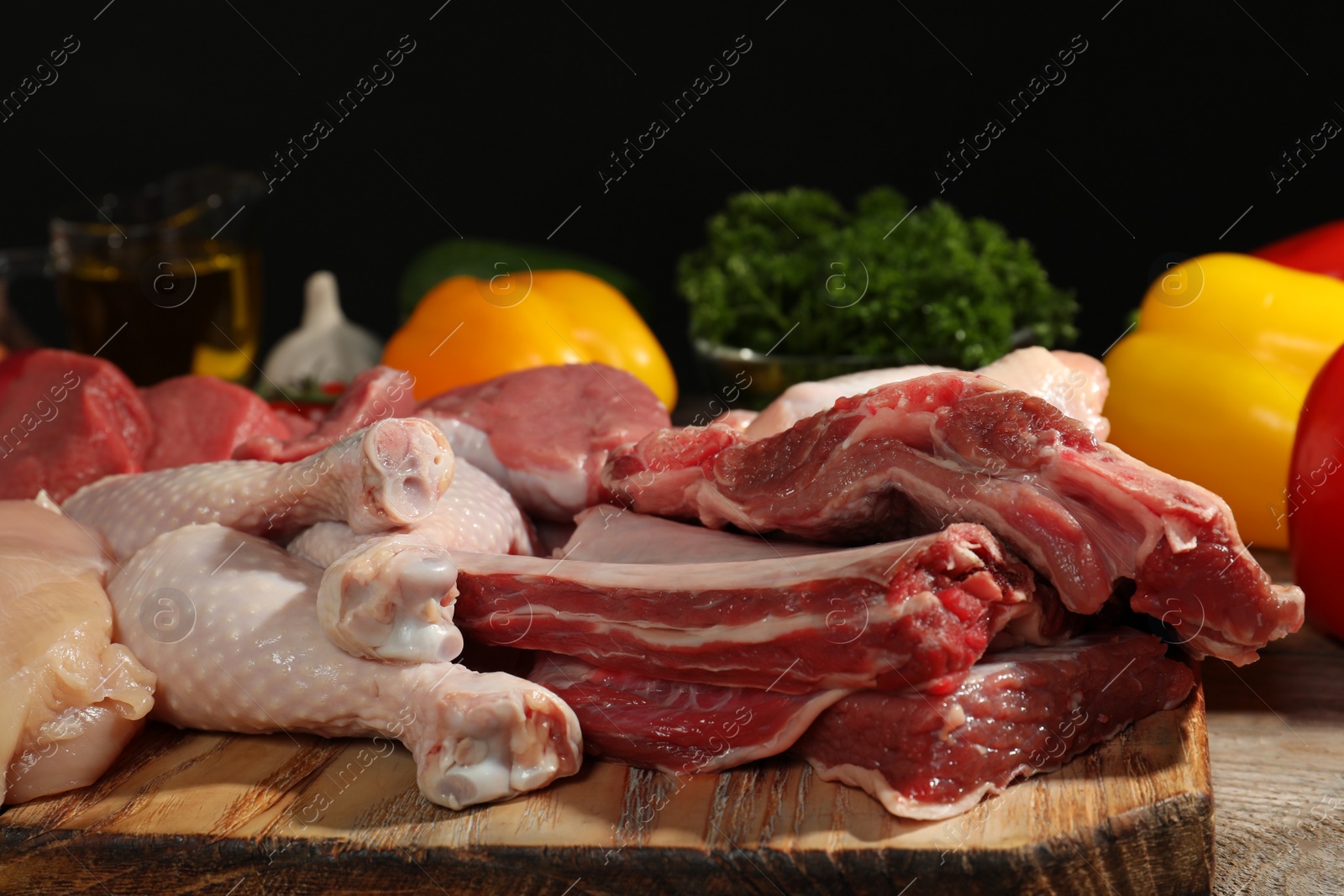 Photo of Wooden board with fresh raw meat on table against dark background