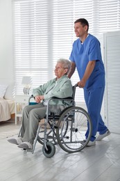 Photo of Caregiver assisting senior woman in wheelchair indoors. Home health care service