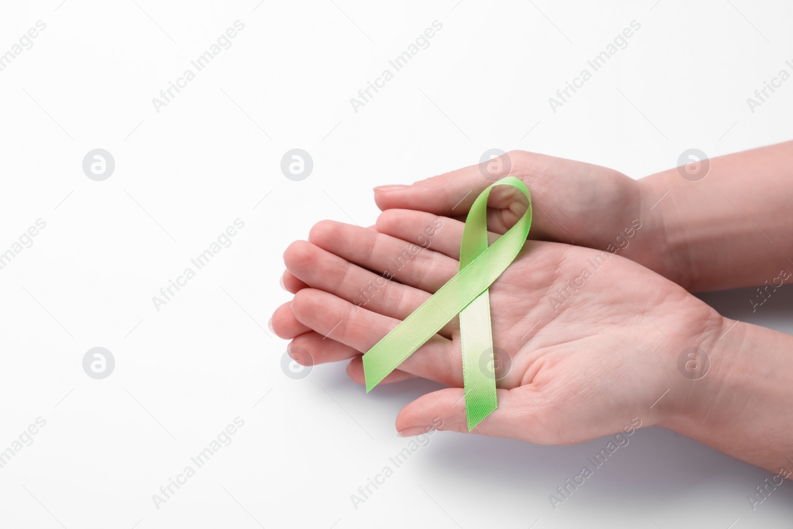 Photo of World Mental Health Day. Woman holding green ribbon on white background, top view with space for text