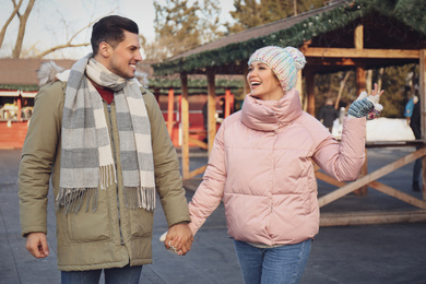 Photo of Happy couple holding hands at winter fair. Christmas celebration