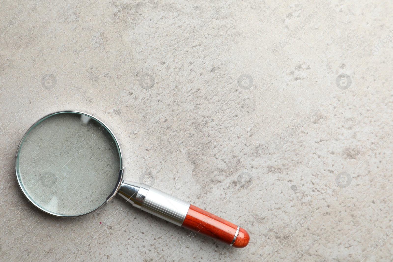 Photo of Top view of magnifier glass on light grey stone background, space for text. Find keywords concept