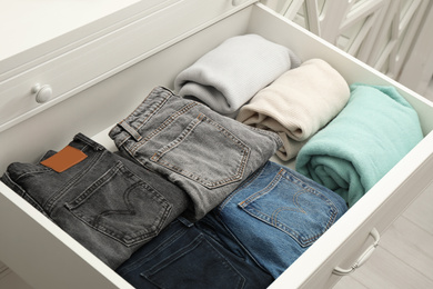Photo of Folded clothes in open drawer. Apparel storage