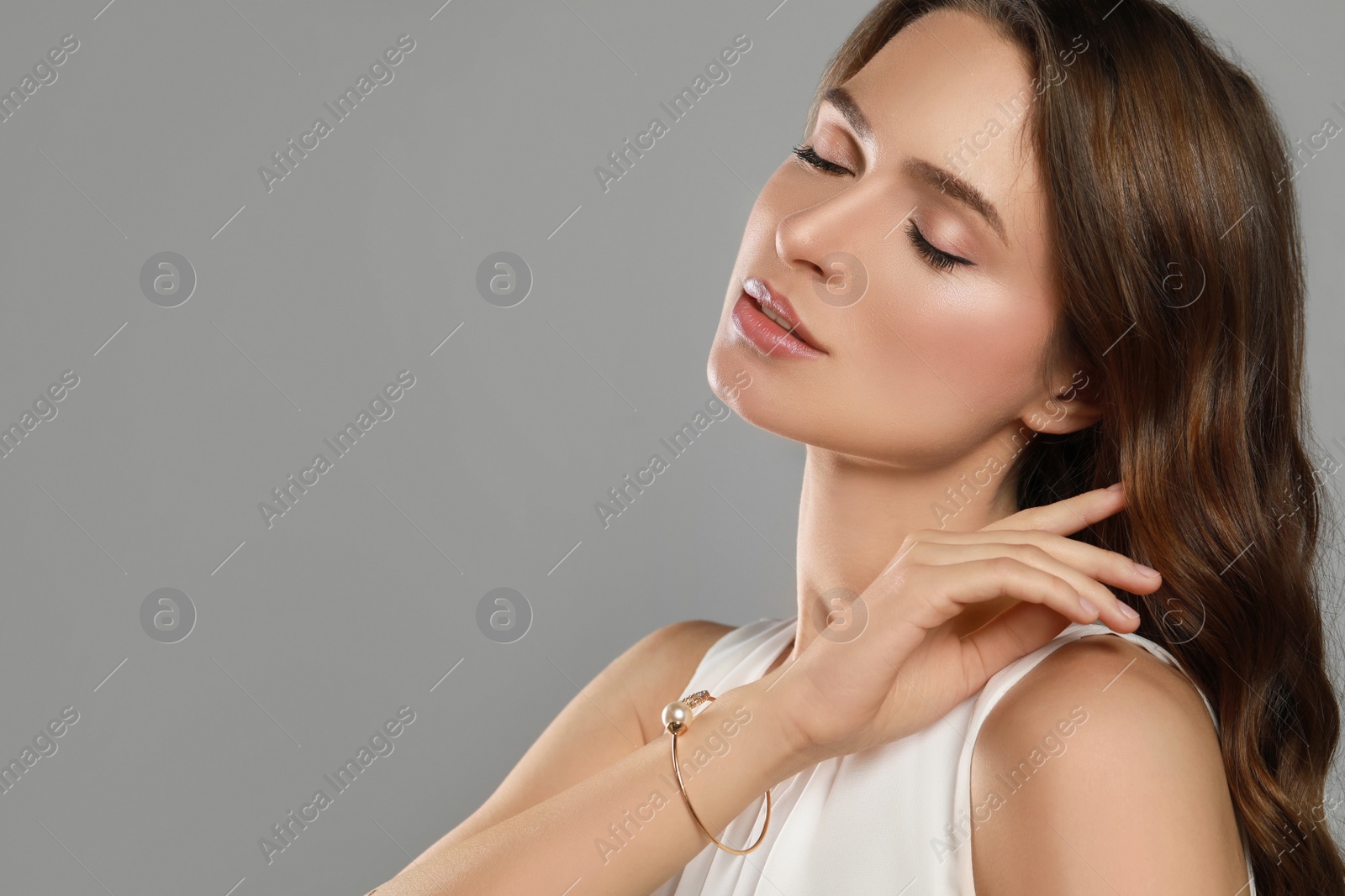 Photo of Young woman wearing elegant pearl jewelry on grey background, space for text