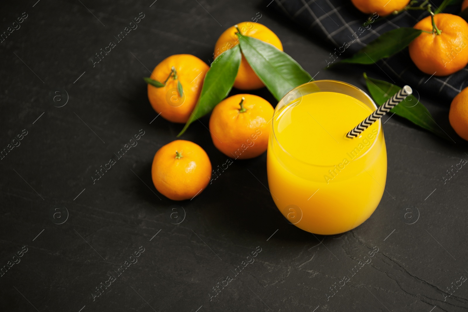 Photo of Glass of fresh tangerine juice and fruits on black table