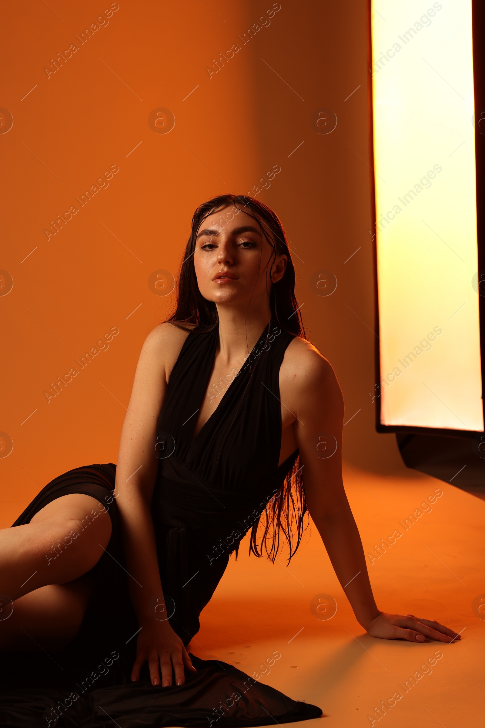 Photo of Beautiful woman in black dress posing on brown background