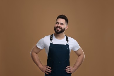 Smiling man in kitchen apron on brown background. Mockup for design