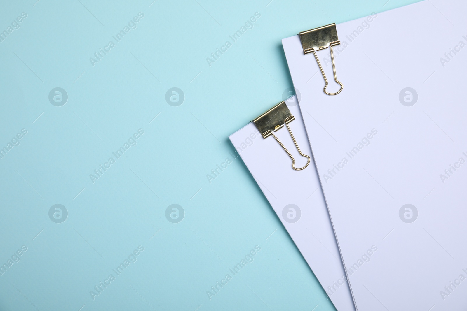 Photo of Sheets of paper with clips on light blue background, top view