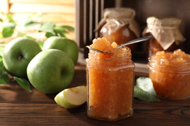 Photo of Delicious apple jam and fresh fruits on wooden, selective focus