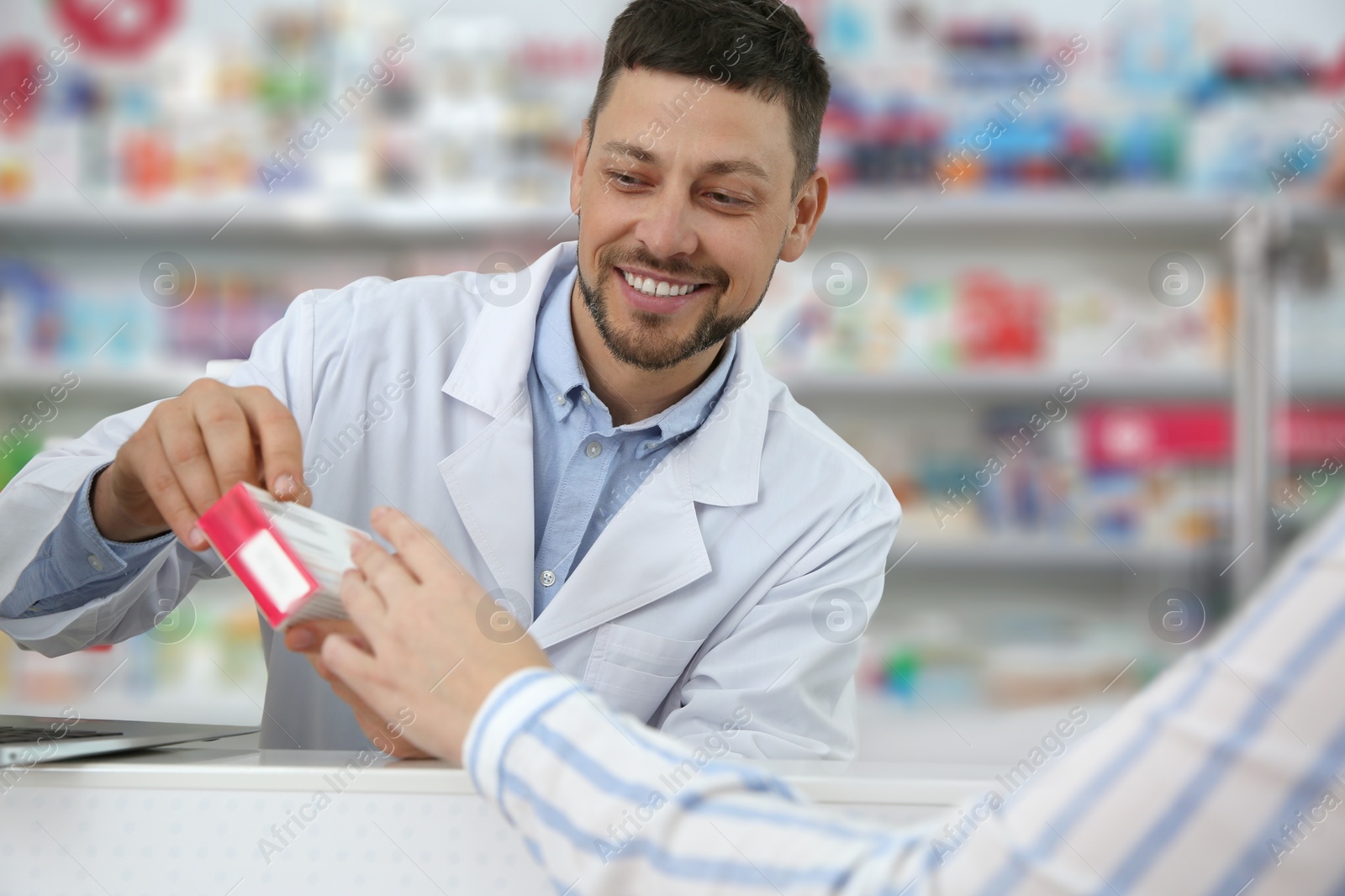 Photo of Professional pharmacist giving medicine to customer in drugstore