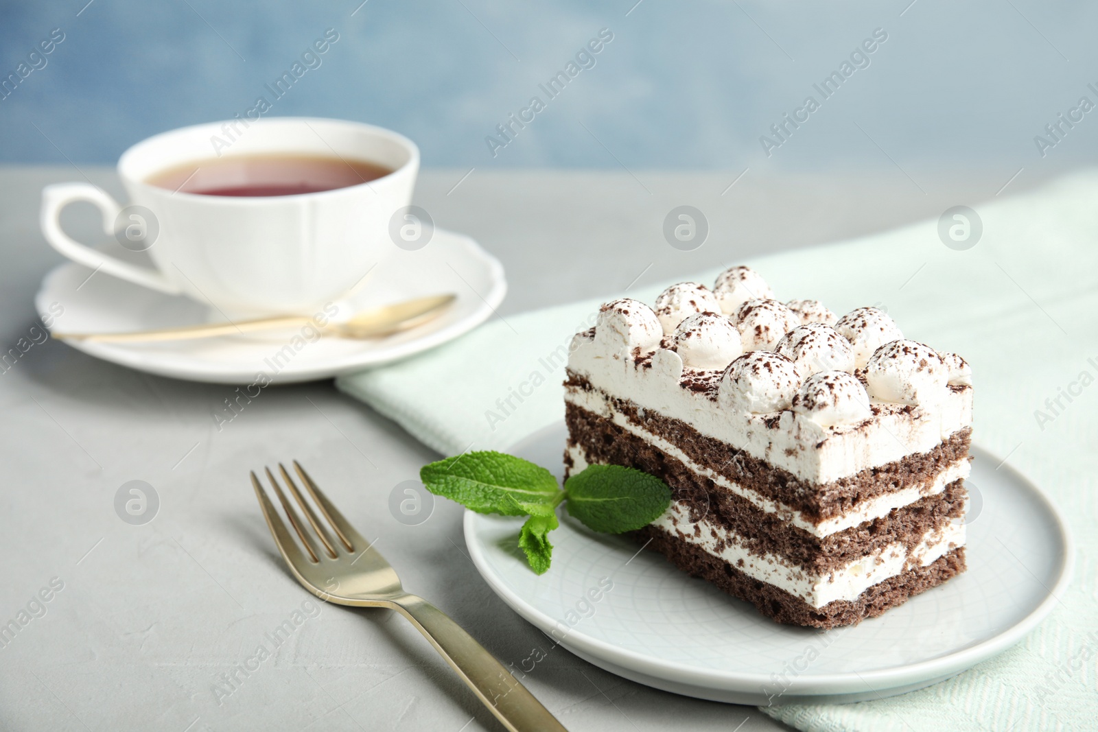 Photo of Delicious tiramisu cake with cup on table, space for text