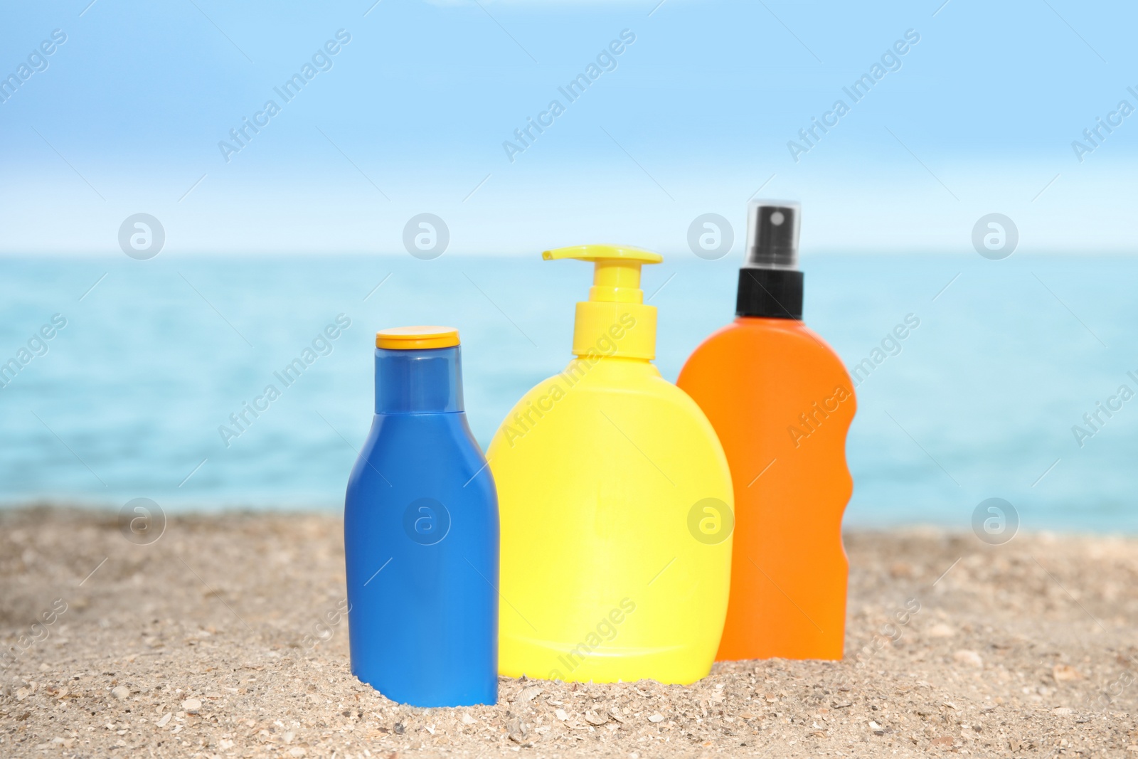 Photo of Bottles of sun protection body cream on beach, space for design