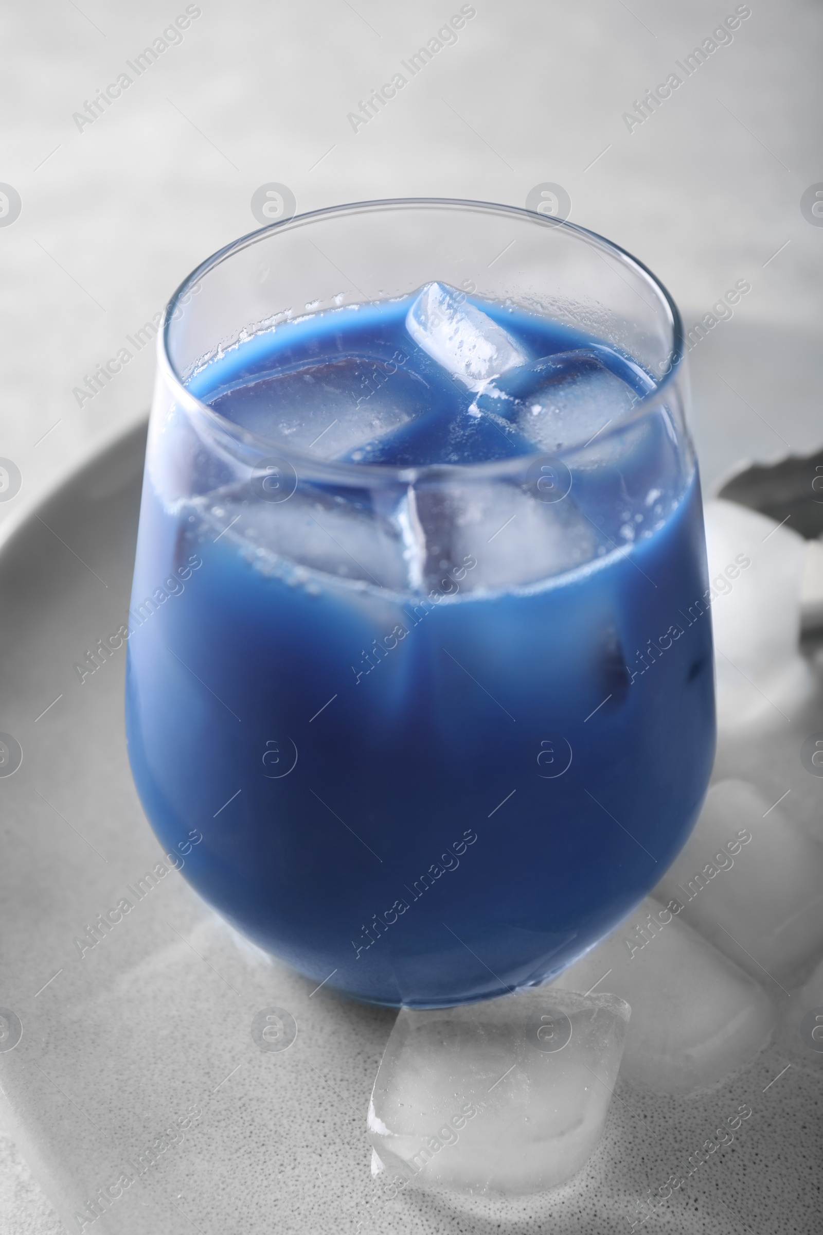 Photo of Delicious blue matcha tea with ice cubes on plate, closeup