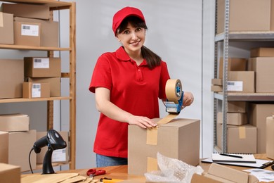 Parcel packing. Post office worker taping box at wooden table indoors