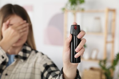 Photo of Woman using pepper spray indoors, focus on hand