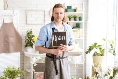 Male florist holding OPEN sign at workplace