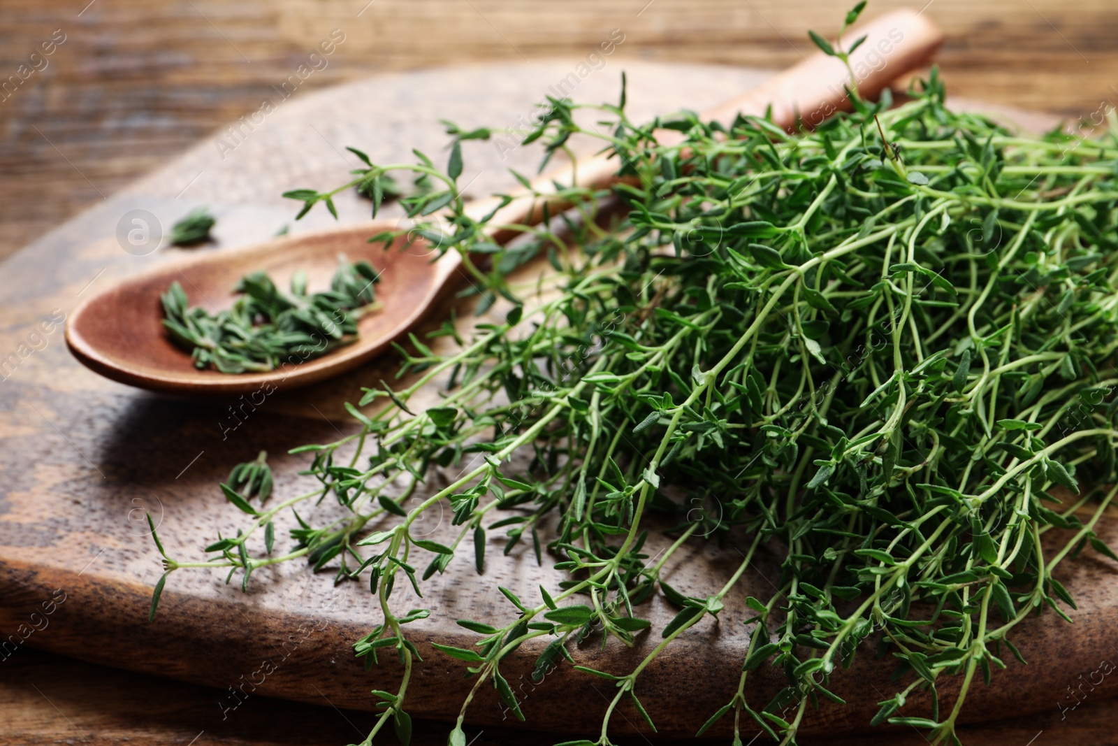 Photo of Bunch of aromatic thyme on wooden table, closeup