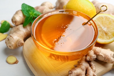 Photo of Honey, ginger and lemon on white table, closeup. Natural cold remedies