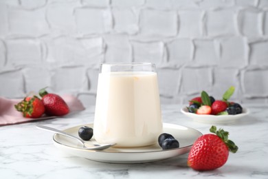 Photo of Tasty yogurt in glass and berries on white marble table