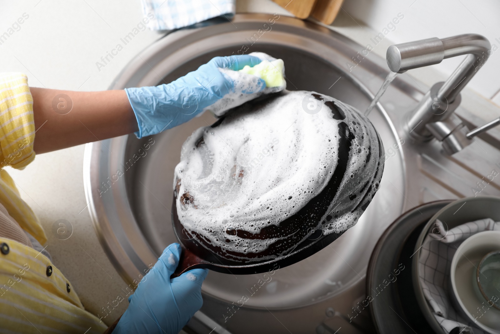 Photo of Woman washing dirty frying pan in sink, above view