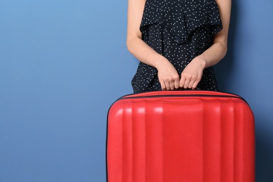 Photo of Young woman with suitcase on color background