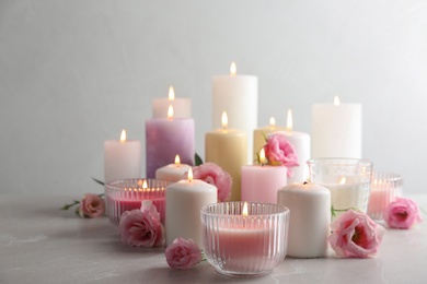 Photo of Composition with burning candles on table against light background
