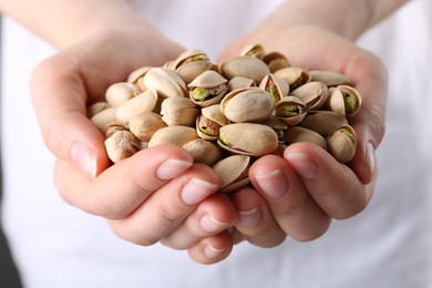 Photo of Woman holding handful of tasty pistachios, closeup