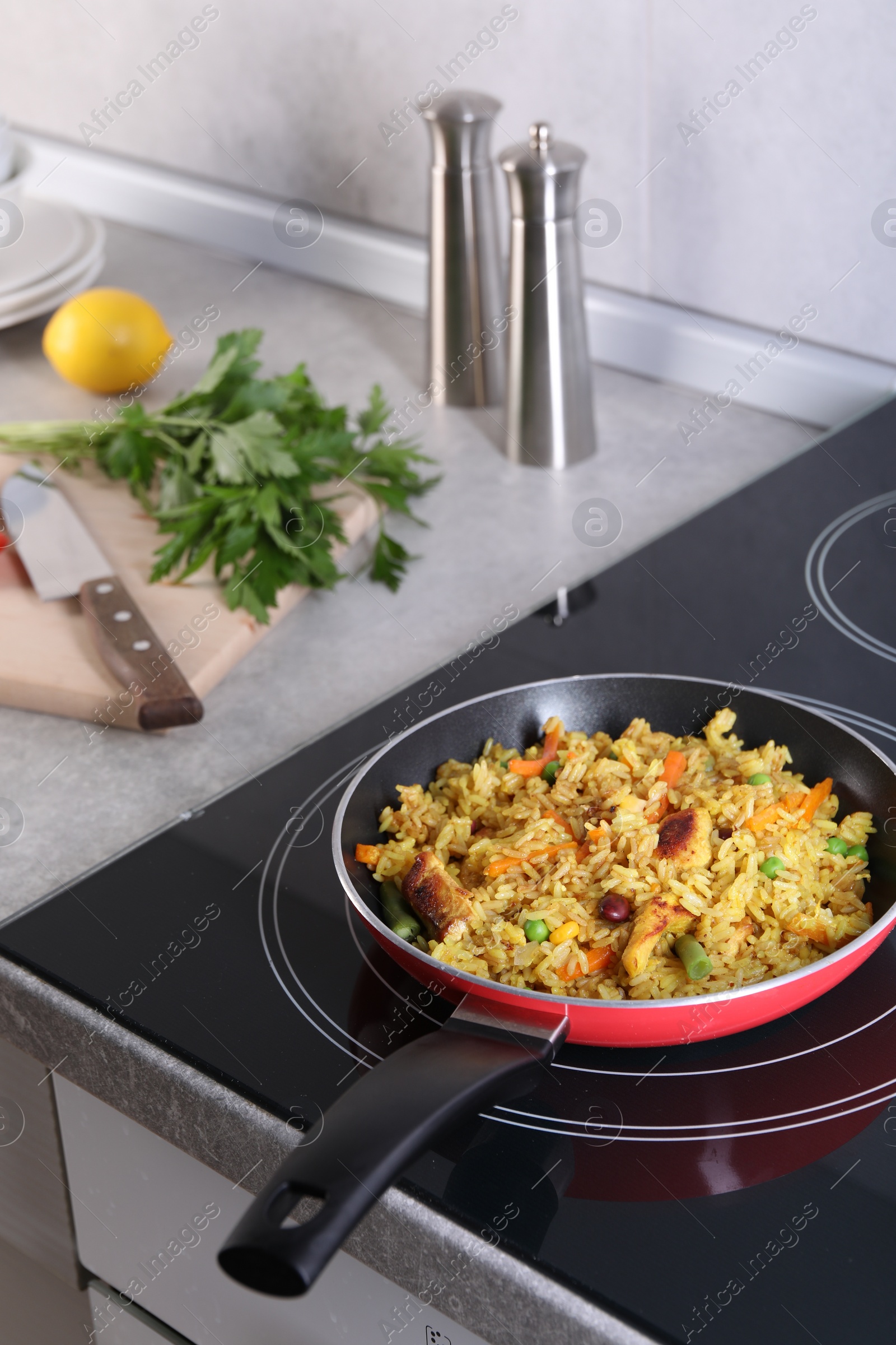 Photo of Tasty rice with meat and vegetables in frying pan on induction cooktop