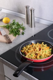Tasty rice with meat and vegetables in frying pan on induction cooktop