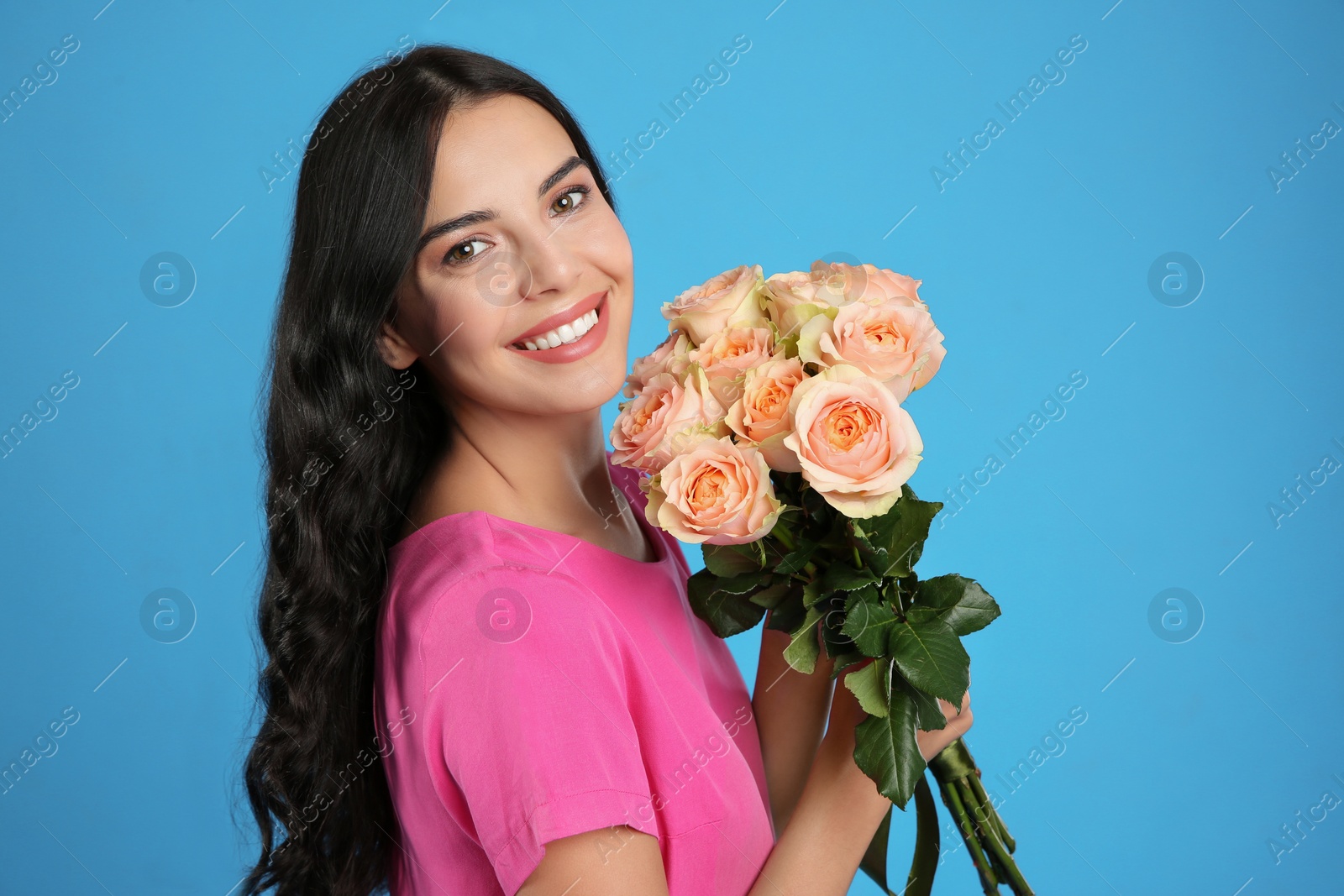 Photo of Portrait of smiling woman with beautiful bouquet on light blue background