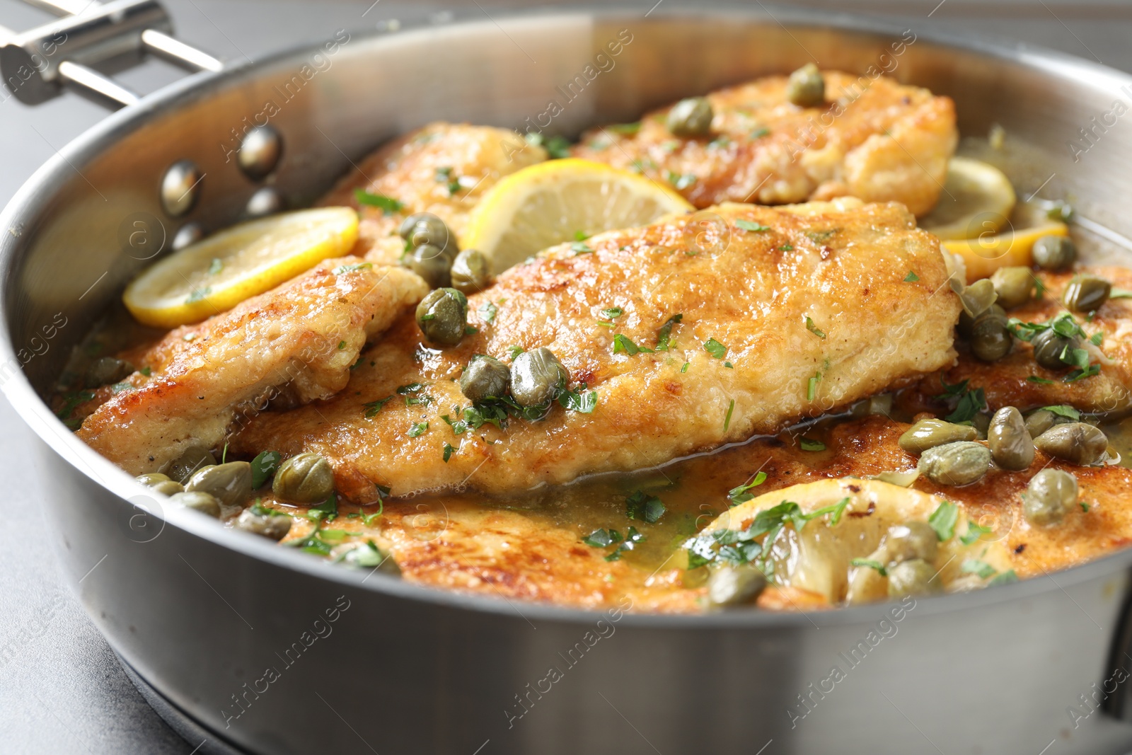 Photo of Delicious chicken piccata on grey table, closeup