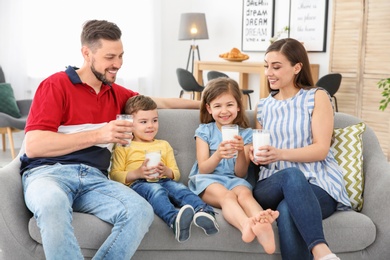 Photo of Happy family with glasses of milk in living room