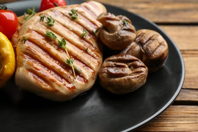 Photo of Tasty grilled chicken fillet with mushrooms on wooden table, closeup